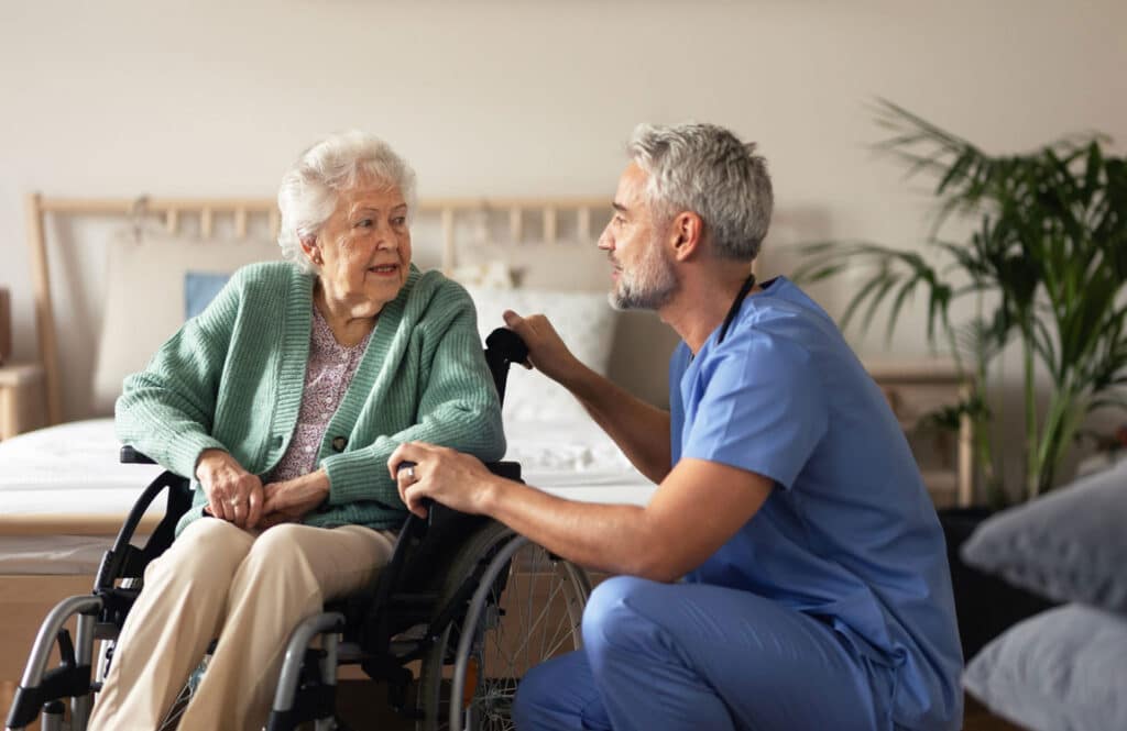 A nurse assists an elderly woman in a wheelchair