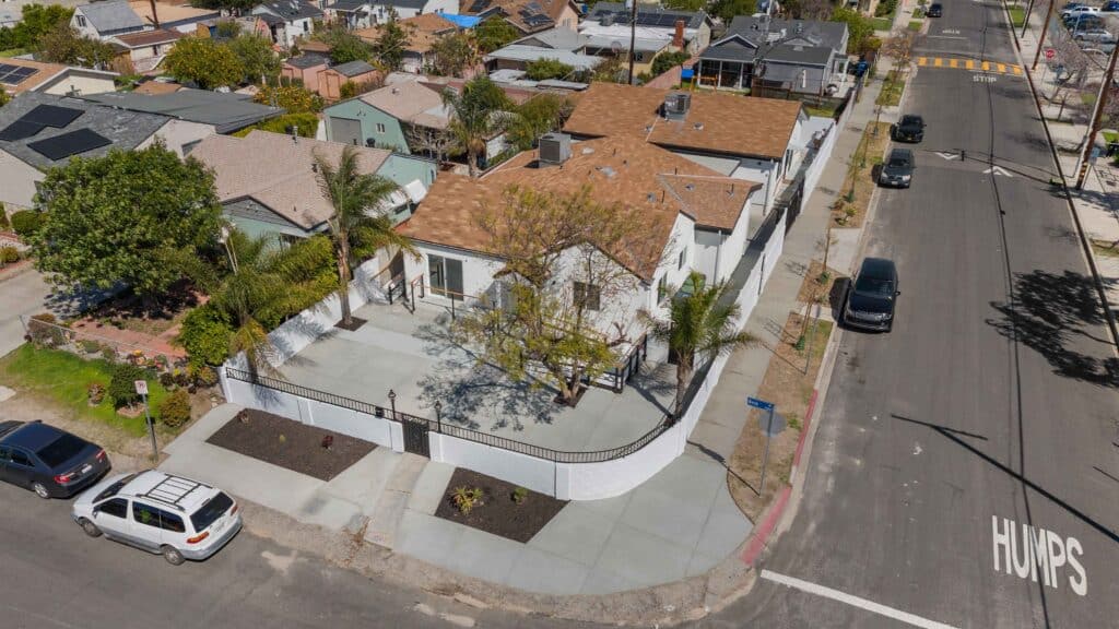 A white house surrounded by a fence and palm trees