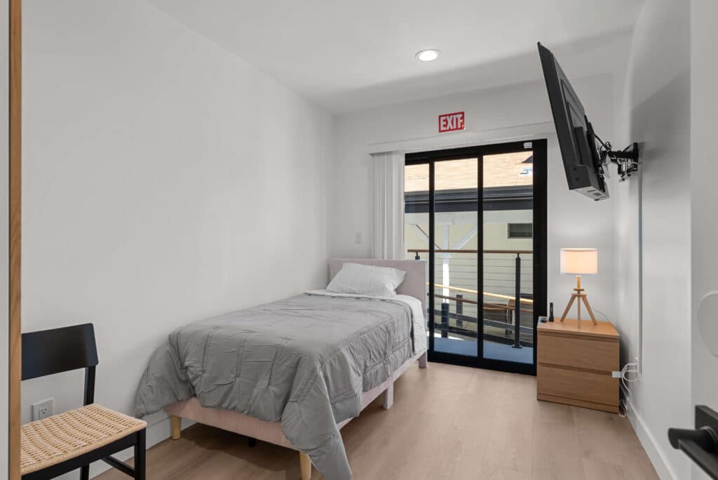 bedroom featuring a bed, a desk, and a television against a neutral-colored wall.