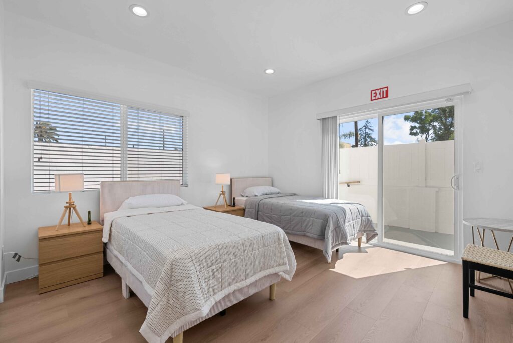 A bedroom featuring two beds and a sliding door, creating a spacious and inviting atmosphere.