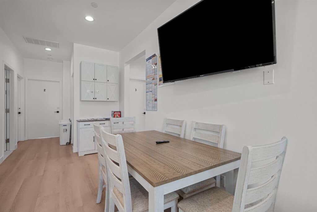 kitchen featuring a table with chairs and a flat-screen TV mounted on the wall.